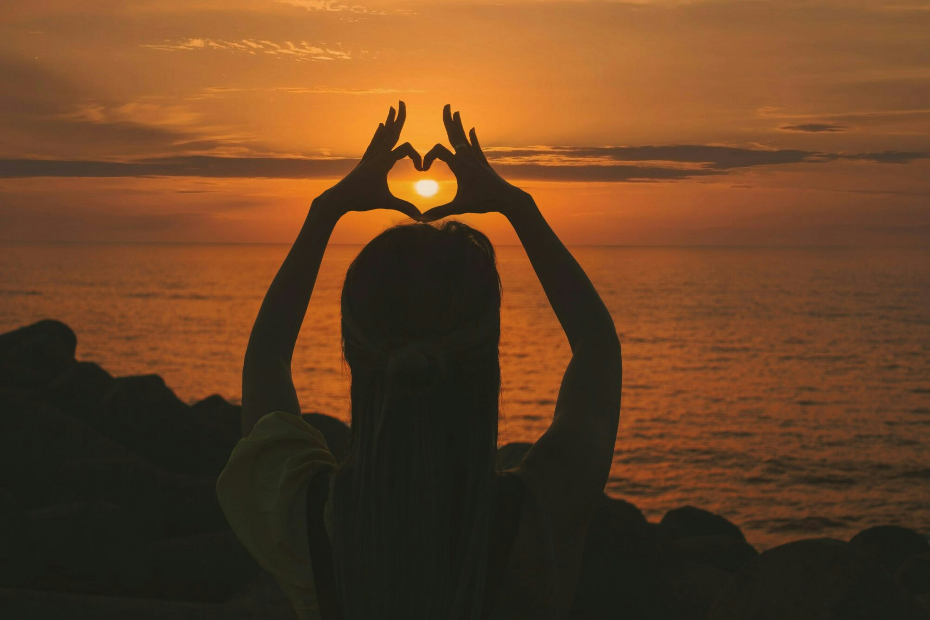 woman holding up hands in shape of heart